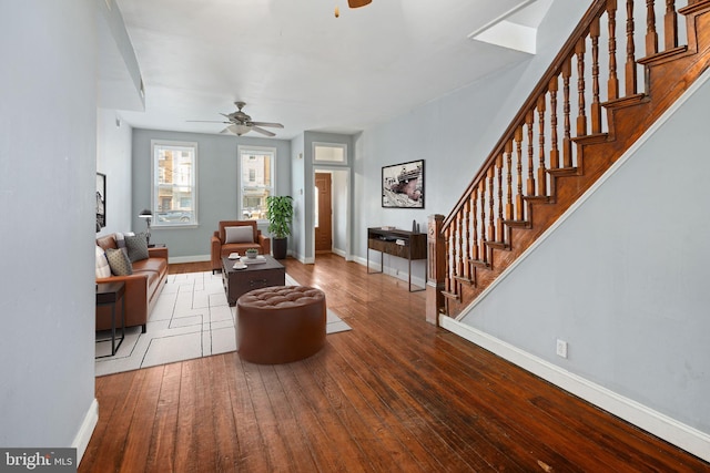 living room with baseboards, stairs, a ceiling fan, and wood-type flooring