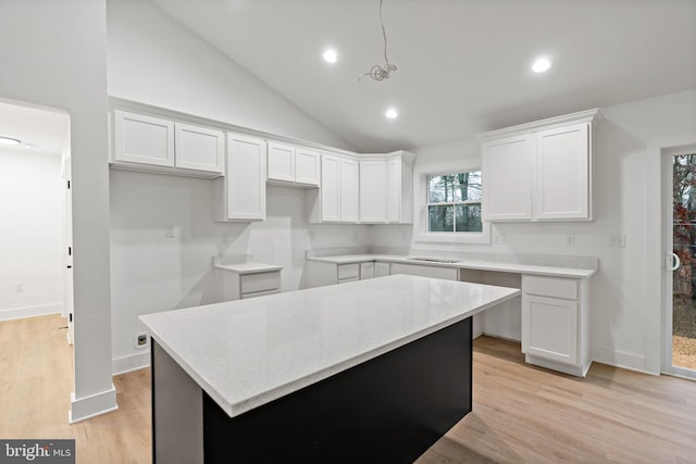 kitchen with vaulted ceiling, pendant lighting, light hardwood / wood-style flooring, a center island, and white cabinetry