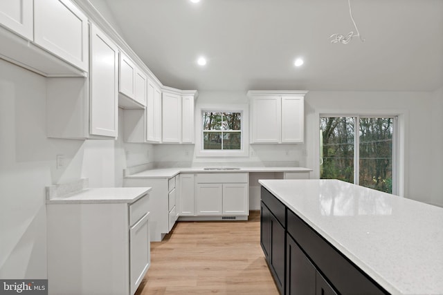 kitchen with plenty of natural light, white cabinets, and light hardwood / wood-style flooring