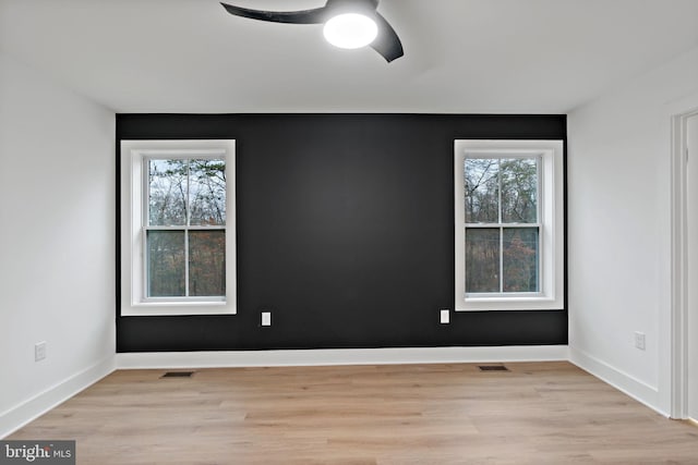 unfurnished room featuring a wealth of natural light, ceiling fan, and light wood-type flooring