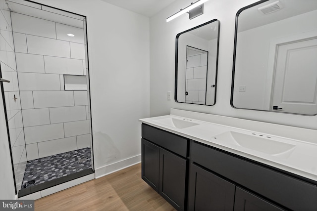 bathroom featuring hardwood / wood-style floors, vanity, and a tile shower