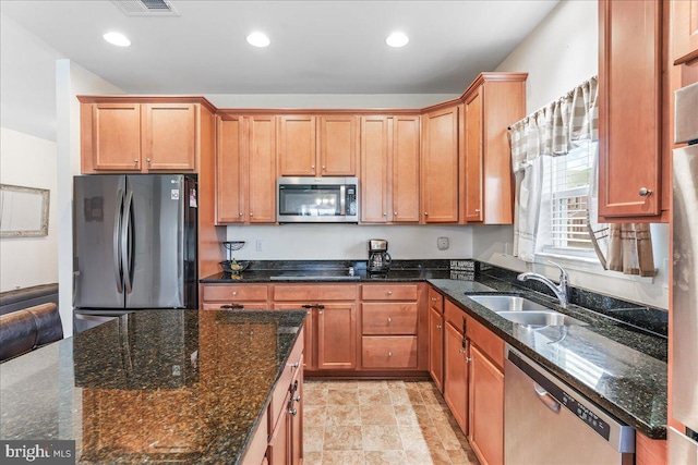 kitchen featuring sink, stainless steel appliances, and dark stone countertops