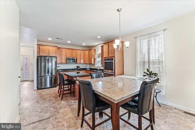 kitchen featuring appliances with stainless steel finishes, pendant lighting, and a notable chandelier