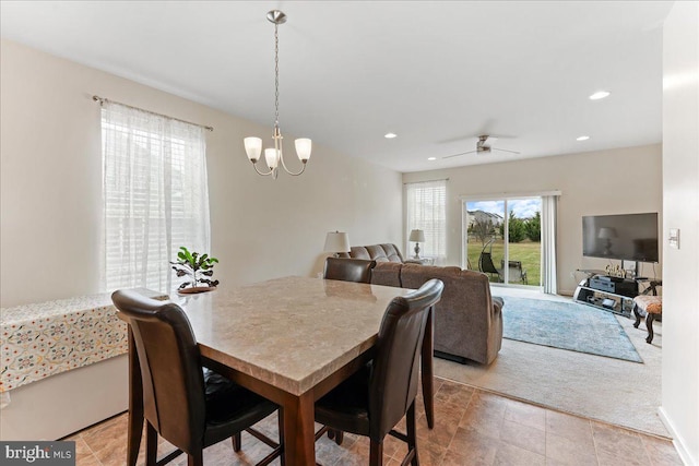 dining space with light colored carpet and ceiling fan with notable chandelier