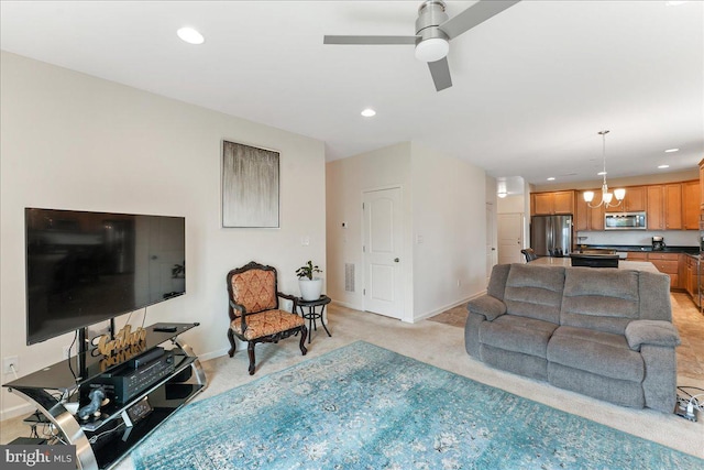 carpeted living room featuring ceiling fan with notable chandelier