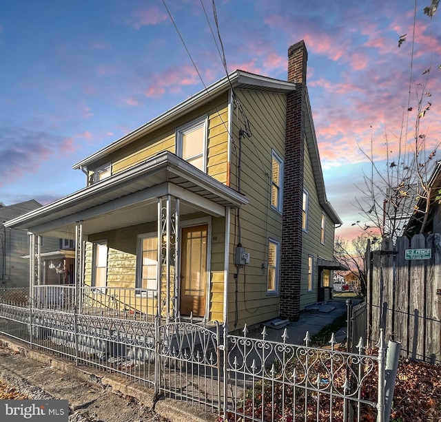 40 W Ridge St, Summit Hill, PA 18250 - view of front of house with covered porch, a fenced front yard, and a chimney
