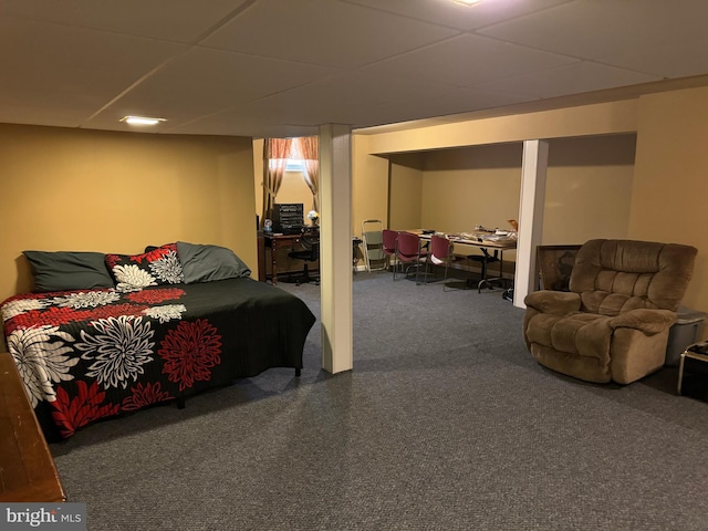 bedroom featuring a drop ceiling and dark colored carpet