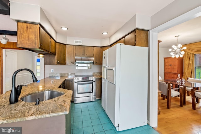 kitchen featuring wood-type flooring, stainless steel range with electric stovetop, white refrigerator with ice dispenser, sink, and kitchen peninsula