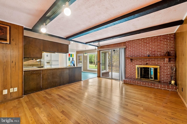 kitchen with wooden walls, a textured ceiling, and light hardwood / wood-style floors