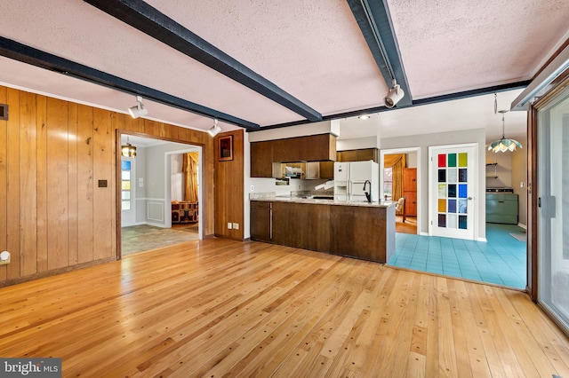 kitchen featuring beamed ceiling, kitchen peninsula, a textured ceiling, and light hardwood / wood-style floors