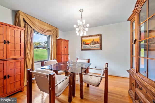 dining area with light wood-type flooring and a notable chandelier