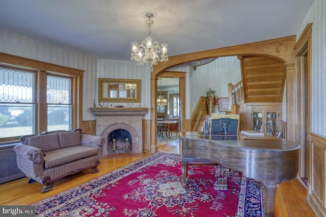 living room with a notable chandelier, hardwood / wood-style flooring, and a brick fireplace