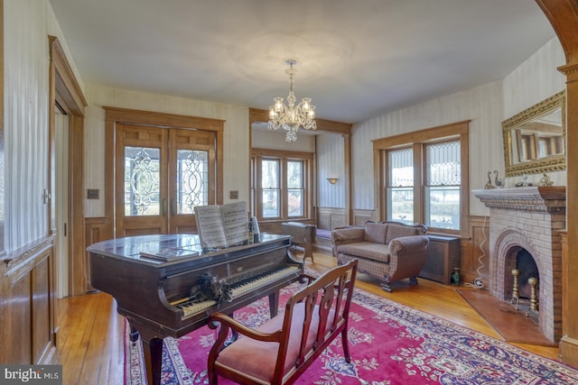 living room with a brick fireplace, light wood-type flooring, and a notable chandelier