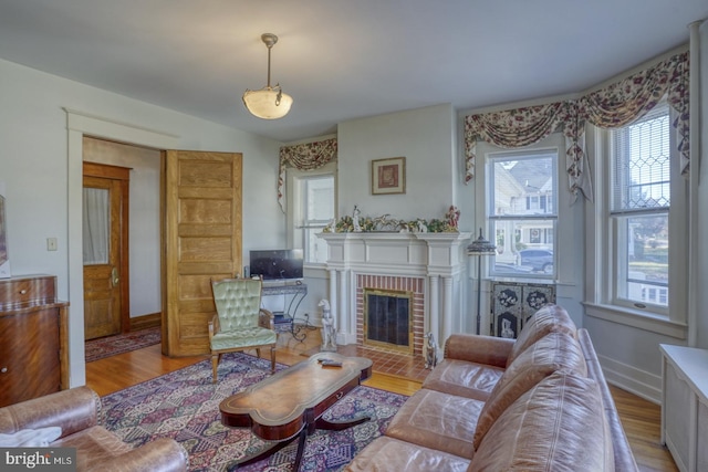 living room with a brick fireplace and light hardwood / wood-style flooring