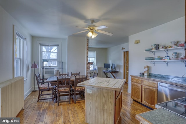 kitchen featuring radiator, a kitchen island, light wood-type flooring, dishwasher, and tile countertops