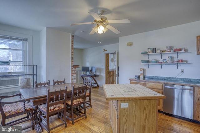 kitchen featuring tile countertops, ceiling fan, a kitchen island, light wood-type flooring, and dishwasher