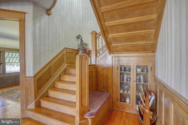 stairway with wood walls and hardwood / wood-style flooring