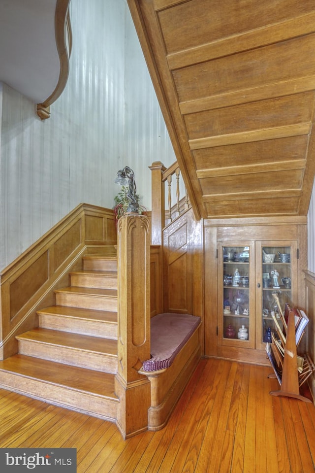 stairway with hardwood / wood-style floors, wooden ceiling, wooden walls, and lofted ceiling