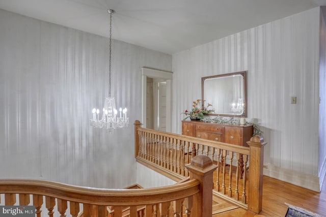 staircase with a chandelier and hardwood / wood-style floors