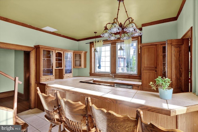 kitchen with a notable chandelier, stainless steel dishwasher, light tile patterned flooring, tile counters, and decorative light fixtures