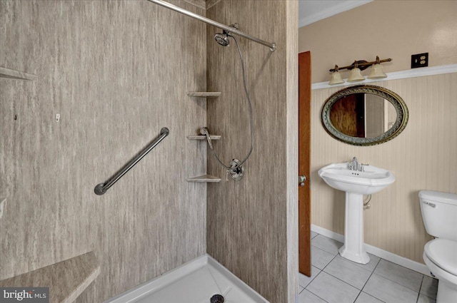 bathroom featuring tiled shower, crown molding, toilet, and tile patterned flooring