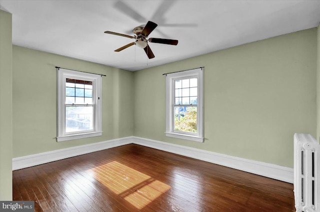 empty room featuring radiator, dark hardwood / wood-style flooring, and plenty of natural light