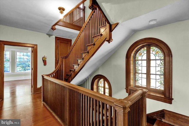 stairs with french doors, a healthy amount of sunlight, wood-type flooring, and lofted ceiling