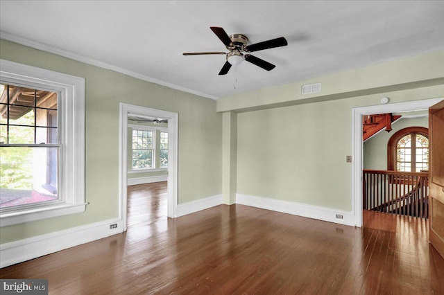 empty room with ceiling fan, a healthy amount of sunlight, dark hardwood / wood-style flooring, and crown molding