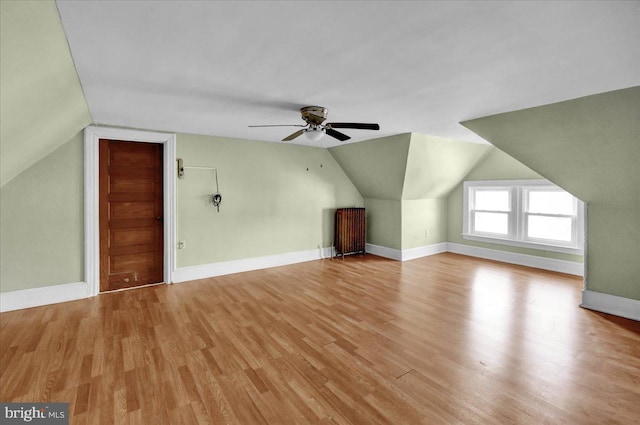 additional living space with lofted ceiling, light hardwood / wood-style flooring, radiator heating unit, and ceiling fan