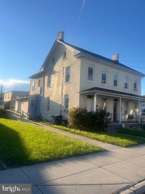 view of side of home featuring covered porch, central AC, and a lawn