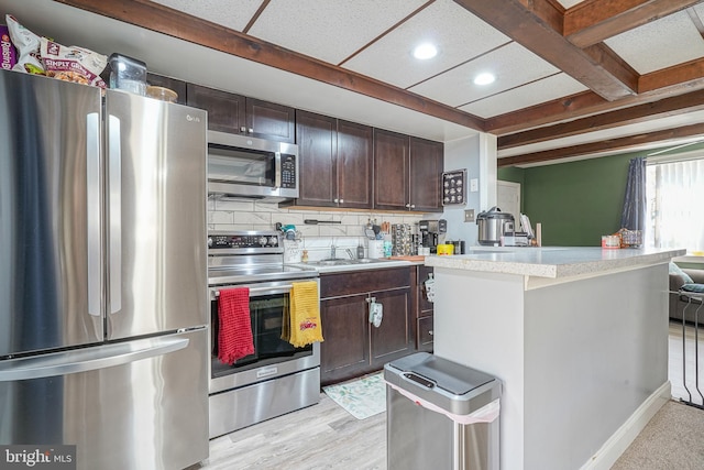 kitchen with beam ceiling, dark brown cabinetry, stainless steel appliances, light hardwood / wood-style flooring, and backsplash