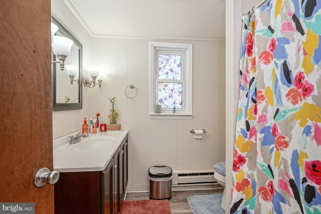 bathroom featuring wood-type flooring, vanity, crown molding, and a baseboard heating unit