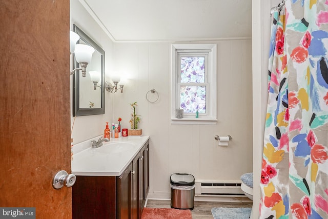 bathroom with vanity, wood walls, a baseboard heating unit, crown molding, and hardwood / wood-style flooring