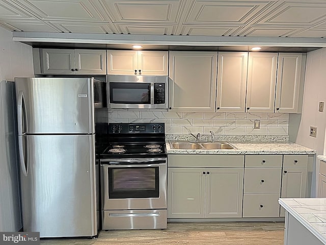 kitchen with decorative backsplash, stainless steel appliances, light hardwood / wood-style floors, and sink