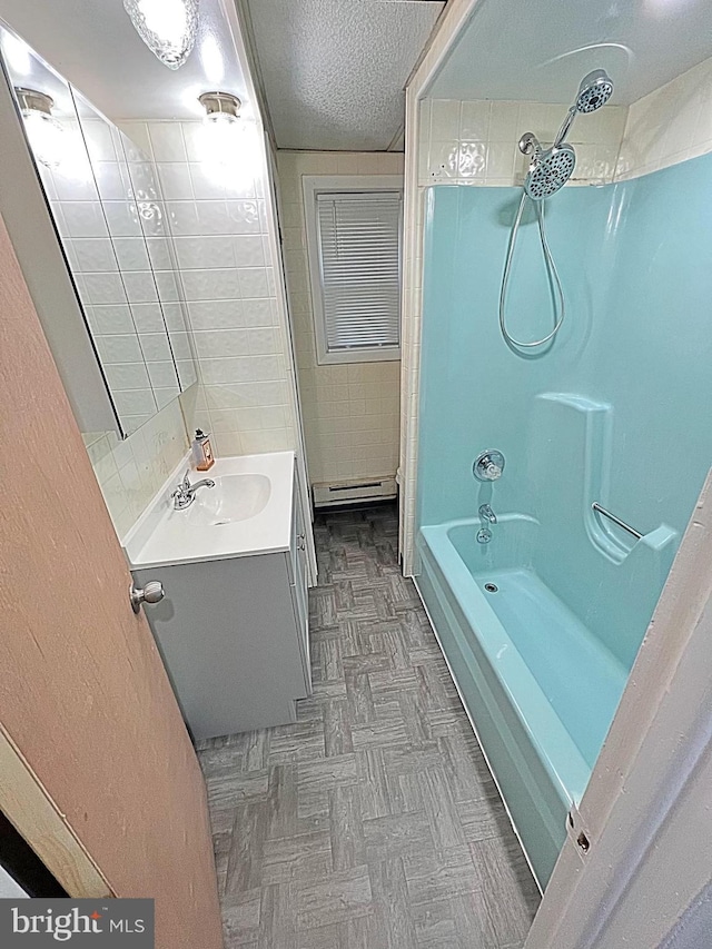 bathroom featuring vanity, a textured ceiling, tiled shower / bath combo, and a baseboard heating unit