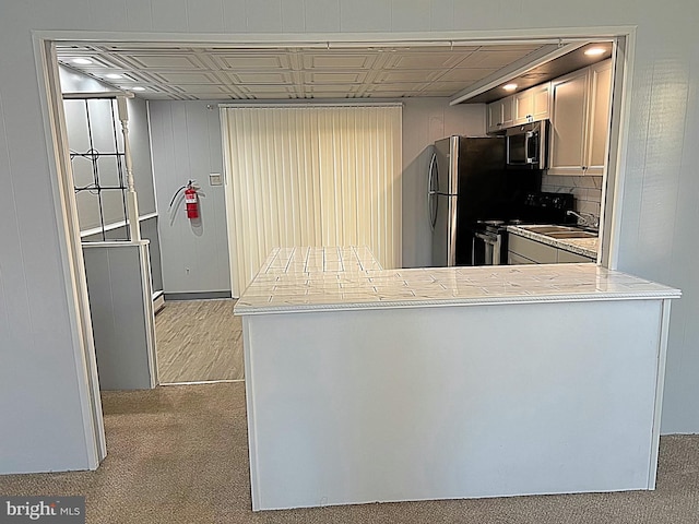 kitchen featuring sink, stainless steel appliances, backsplash, kitchen peninsula, and light carpet