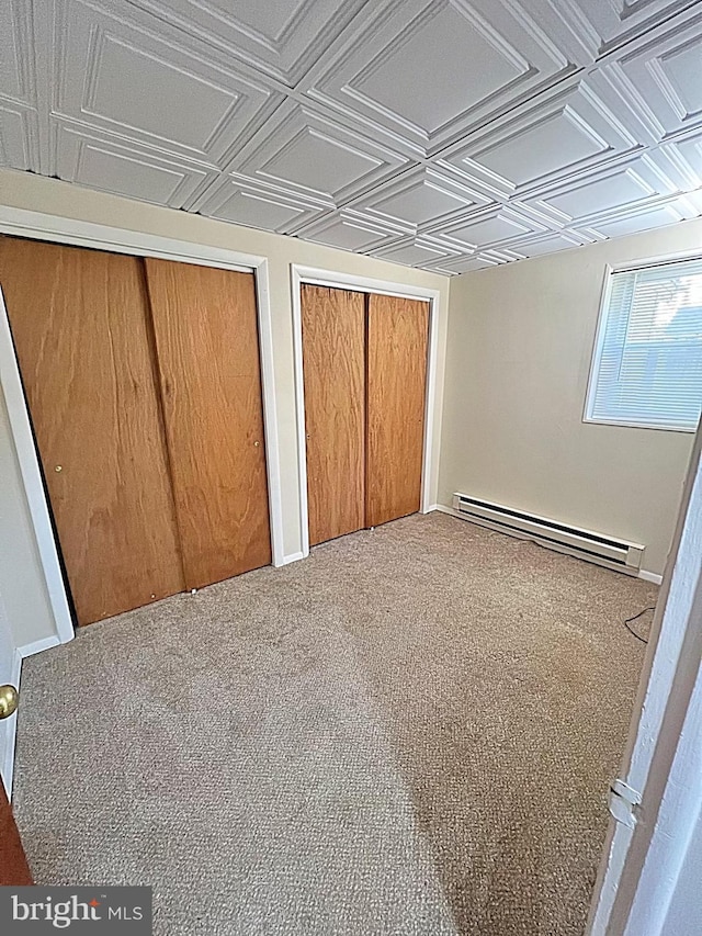 unfurnished bedroom with baseboard heating, a closet, and carpet