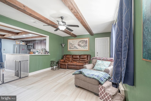 living room with ceiling fan, beamed ceiling, and hardwood / wood-style flooring