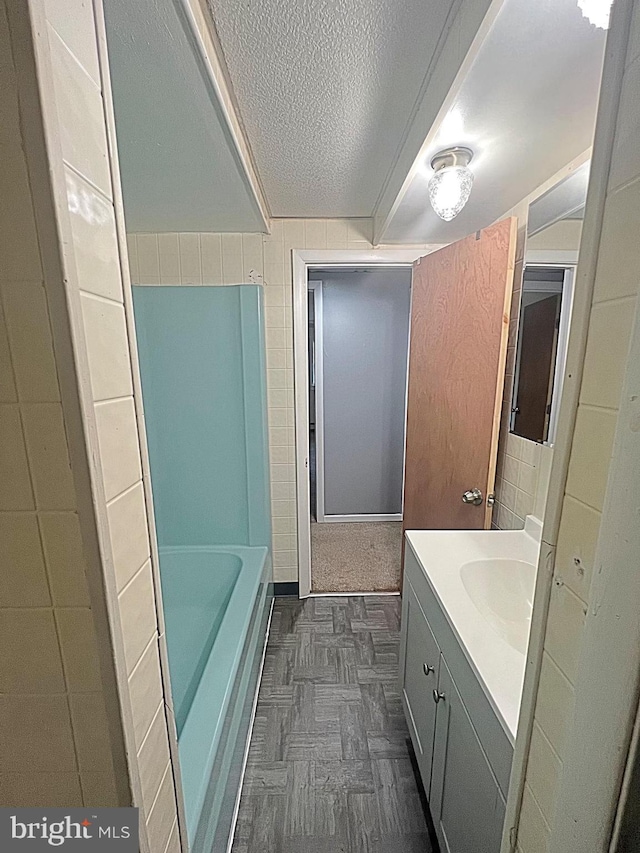 bathroom featuring vanity, a bath, and a textured ceiling