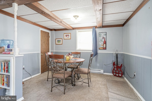 dining space featuring carpet flooring, baseboard heating, beamed ceiling, and wood walls