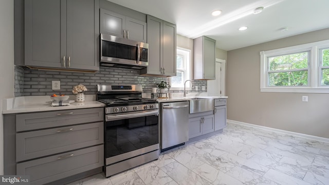 kitchen featuring sink, gray cabinetry, stainless steel appliances, and tasteful backsplash