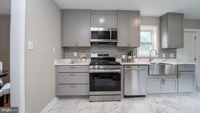 kitchen with gray cabinets, sink, stainless steel appliances, and backsplash