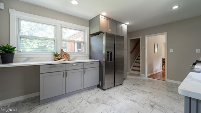 kitchen featuring light stone counters, stainless steel fridge with ice dispenser, and gray cabinets