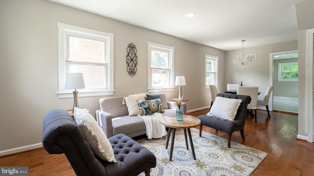 living room with a healthy amount of sunlight, a chandelier, and dark wood-type flooring