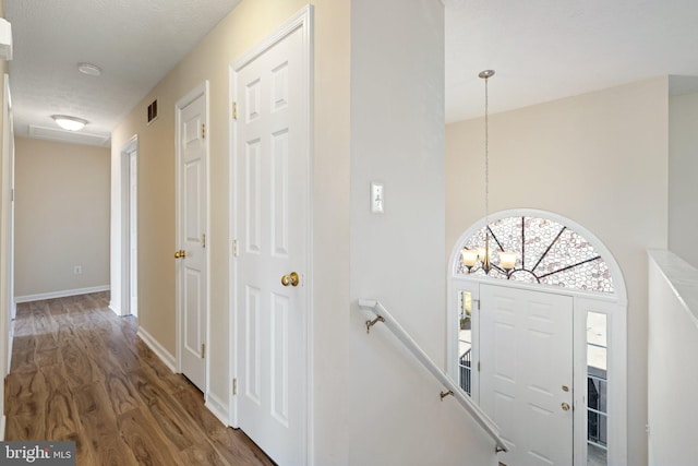 interior space featuring dark wood-type flooring, an inviting chandelier, and a textured ceiling