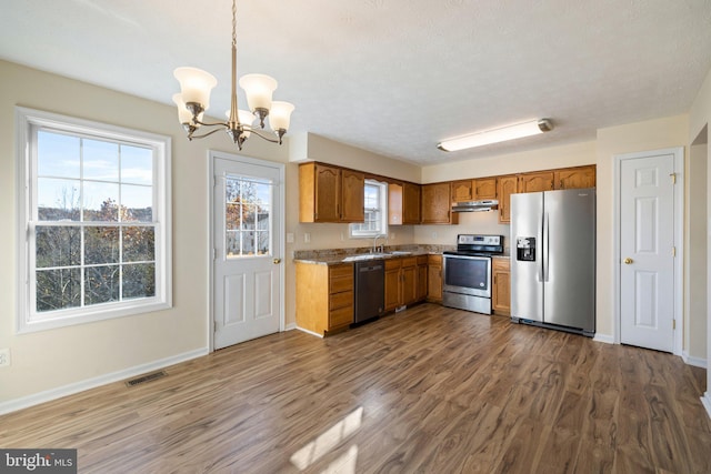 kitchen with stainless steel appliances, dark wood-type flooring, a notable chandelier, sink, and pendant lighting