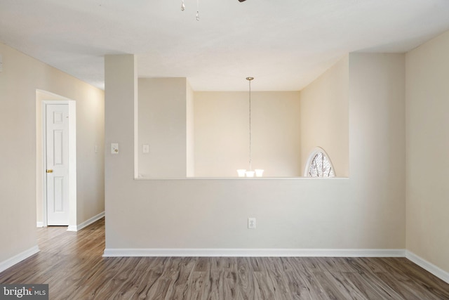 spare room with hardwood / wood-style flooring and a chandelier