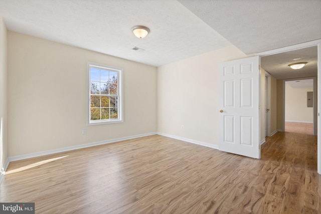 spare room featuring light hardwood / wood-style floors and a textured ceiling