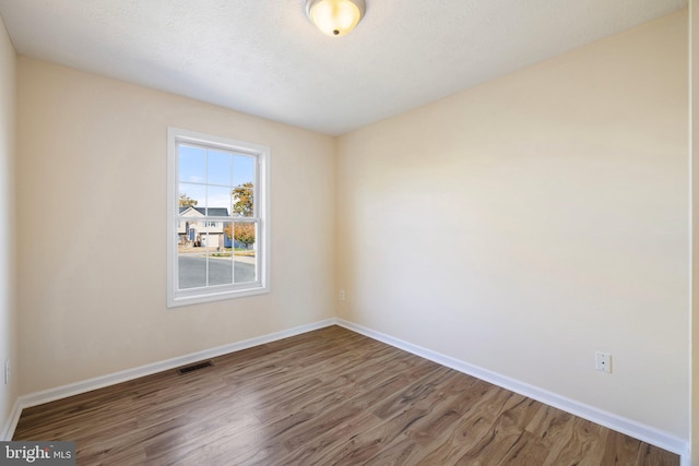 spare room featuring a textured ceiling and dark hardwood / wood-style floors