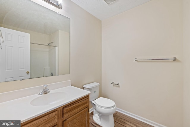 bathroom with wood-type flooring, toilet, a textured ceiling, vanity, and a shower